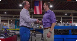 Two men shaking hands in factory.