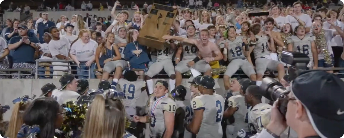 A group of football players proudly holding up a box, showcasing teamwork and celebration on the field.